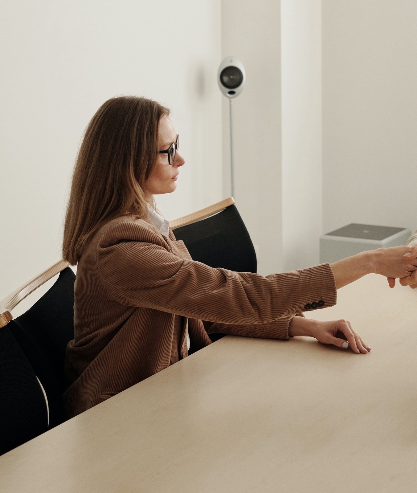 A recruiter reaching across the table to shake hands